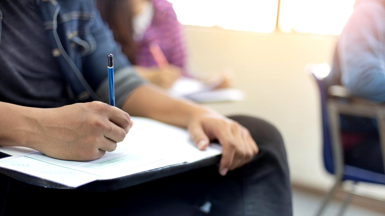 Foto de um concurso público com pessoas se preparando para provas